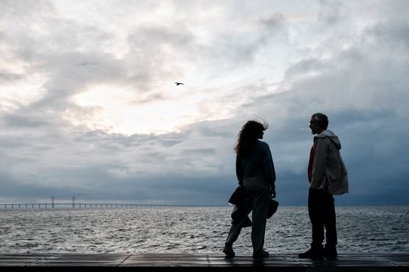 Ett par som står vid havet med Öresundsbron i bakgrunden