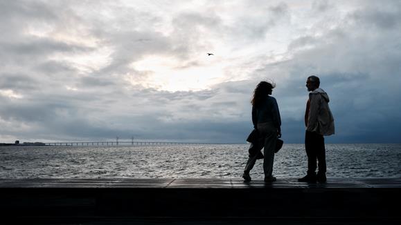 Ett par som står vid havet med Öresundsbron i bakgrunden