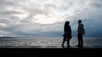 Ett par som står vid havet med Öresundsbron i bakgrunden